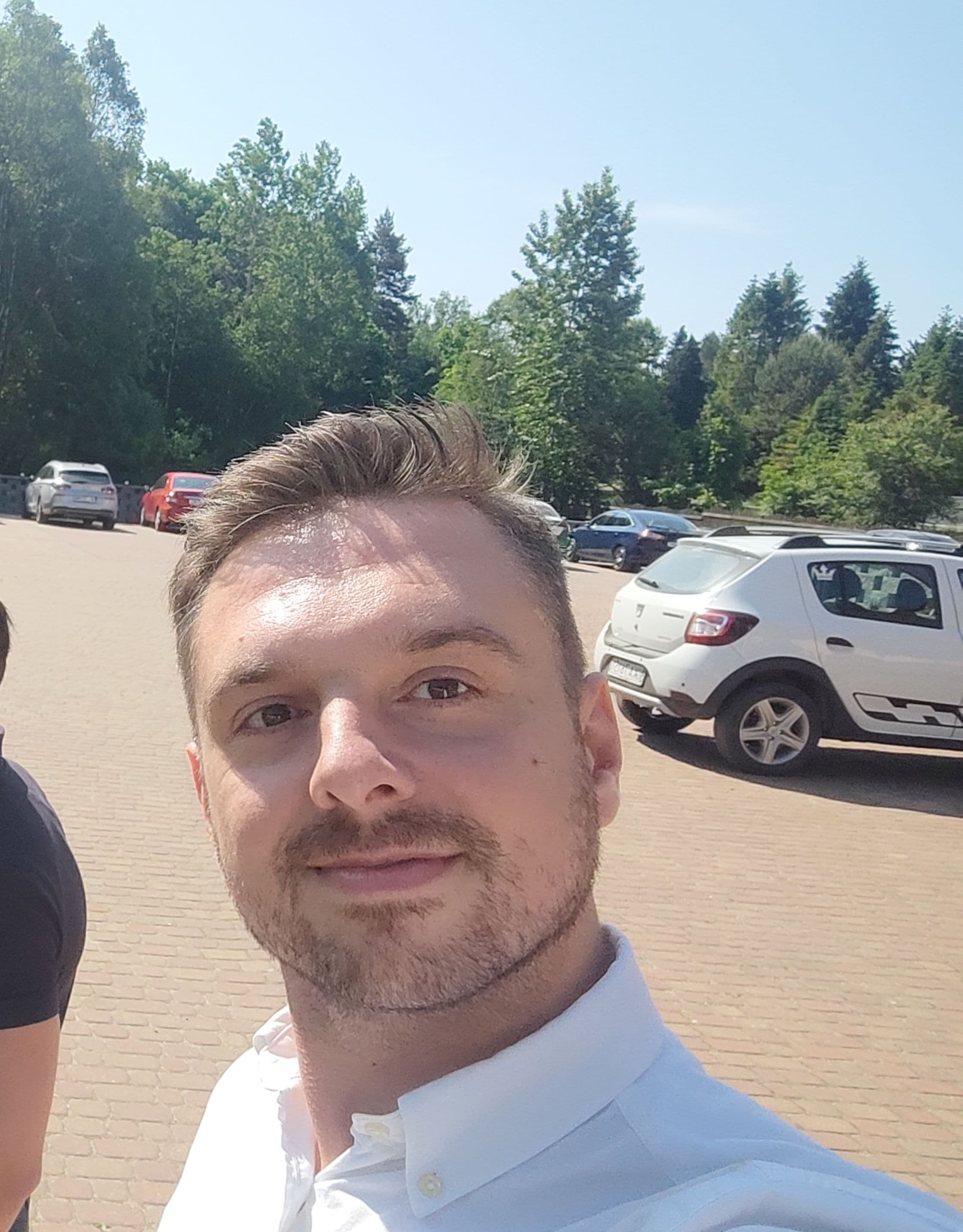 Selfie Marcina zrobione telefonem na parkingu, ostre słońce z góry
