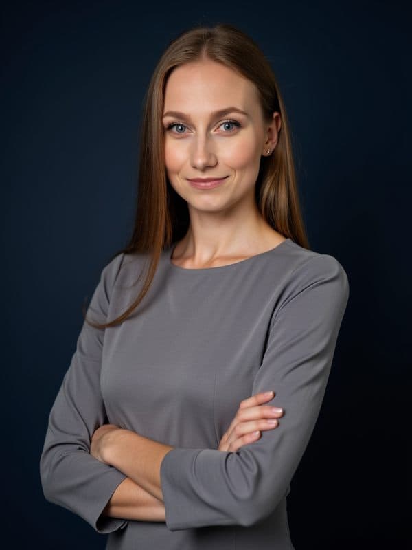 Marta w szarej bluzce ze skrzyżowanymi rękami, ciemne tło studyjne
